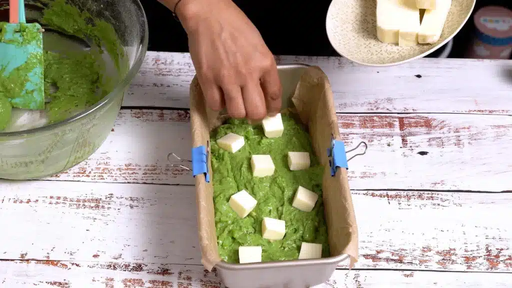 Green Bread - Full of Greens, Cheese and Nuts in a half filled baking pan, add cheese pieces on top