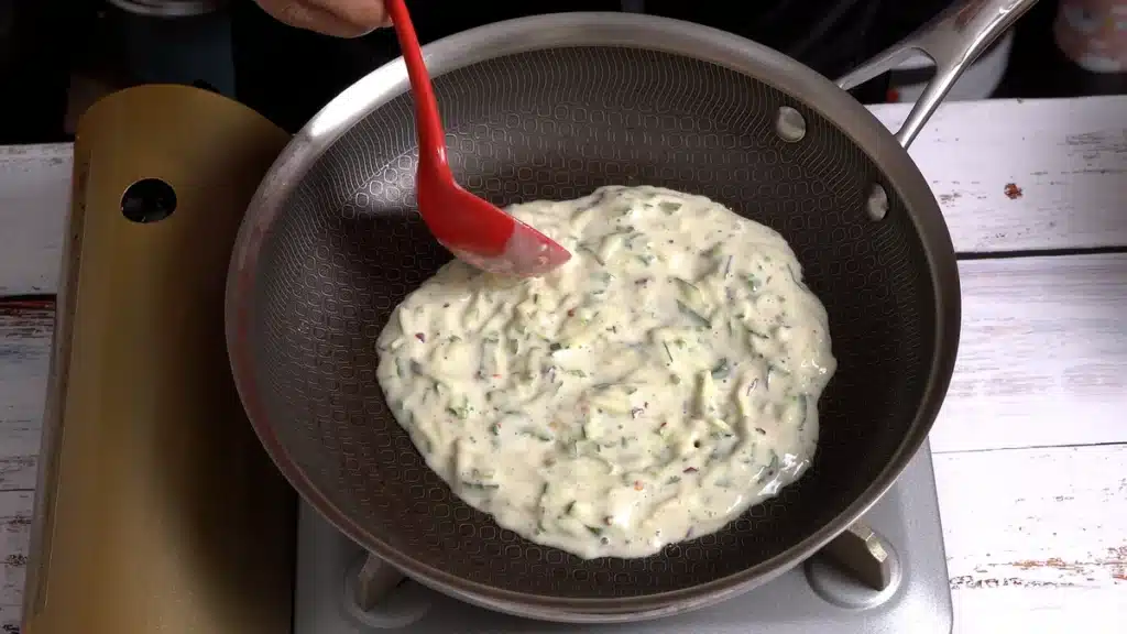 Easy No Dough Zucchini Paratha on a hot pan pour batter to make a thin layer