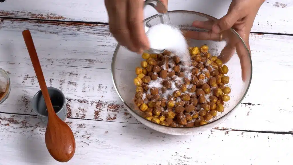 Crunchy Cinnamon Chickpeas - A Perfect Snacks add maple syrup, cinnamon powder and sugar to chickpeas and mix well