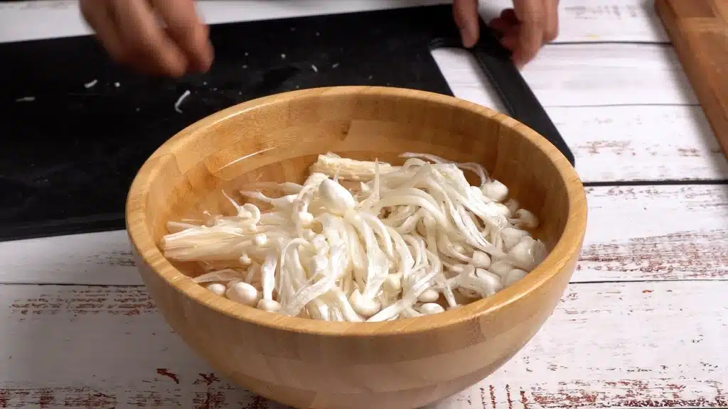 cut and wash enoki mushrooms in water