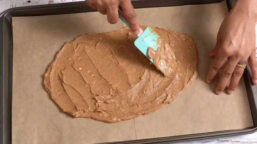 Delicious Buttery Oats Crackers - Sweet and Crunchy spread mixture on a baking tray with parchment paper