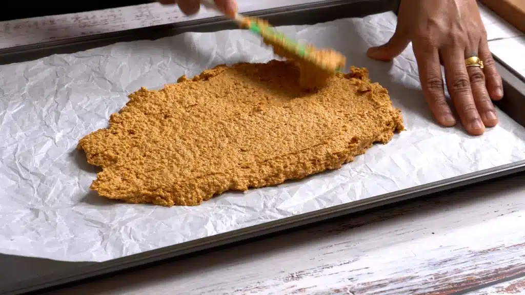 Spicy Oats Cracker : Low in Carb, High in Taste spread mix on a baking tray with parchment paper