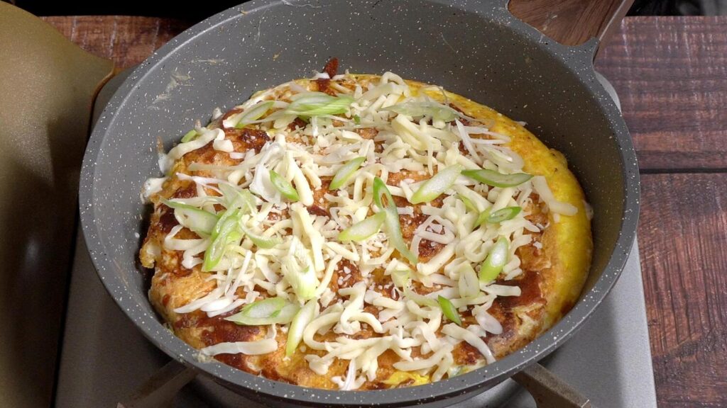 once the eggs slightly cooke, flip it over and add more cheese on top