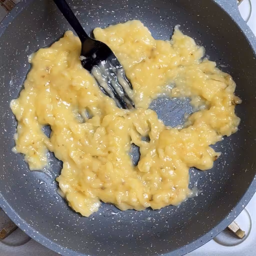 Lightly heat the pan then add oil and spread it evenly, add banana and mash it well.