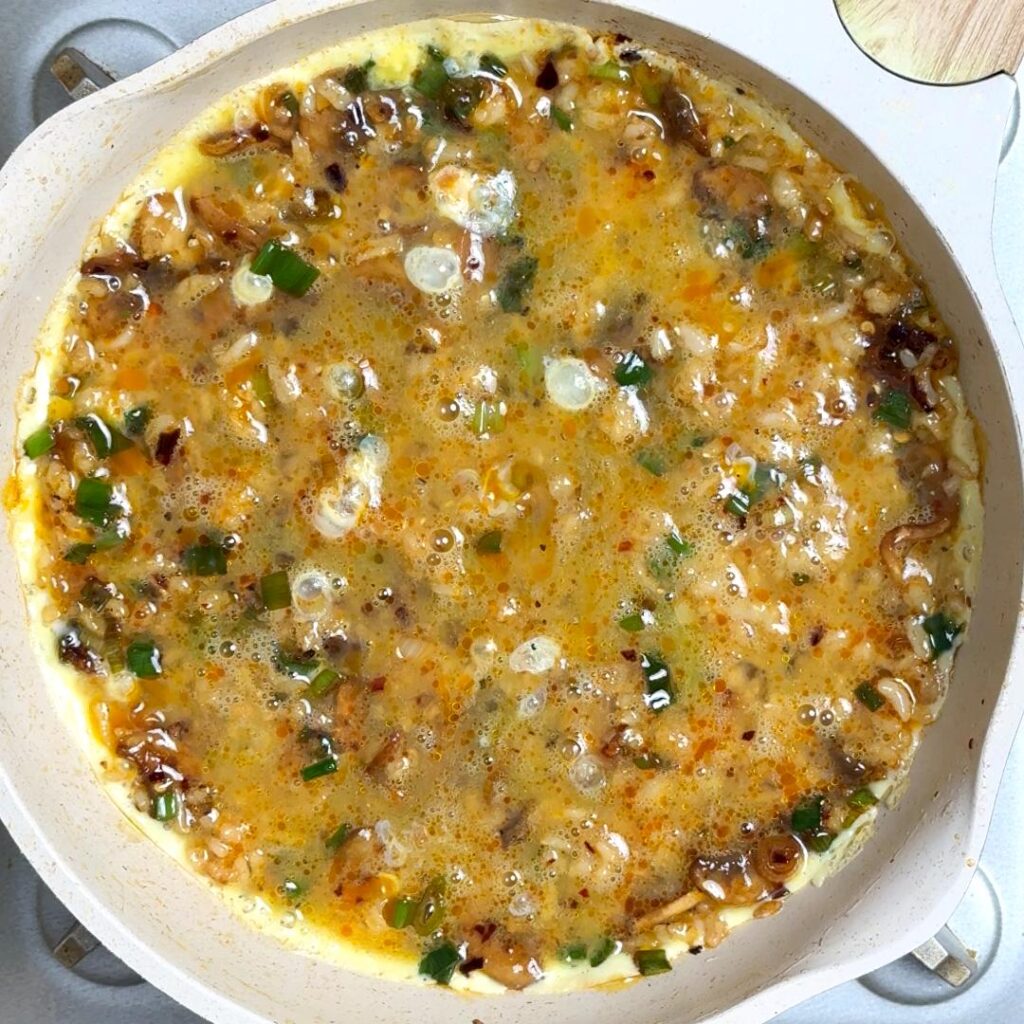 Now add the brown rice and combine everything well, Flatten the rice evenly, then pour the egg