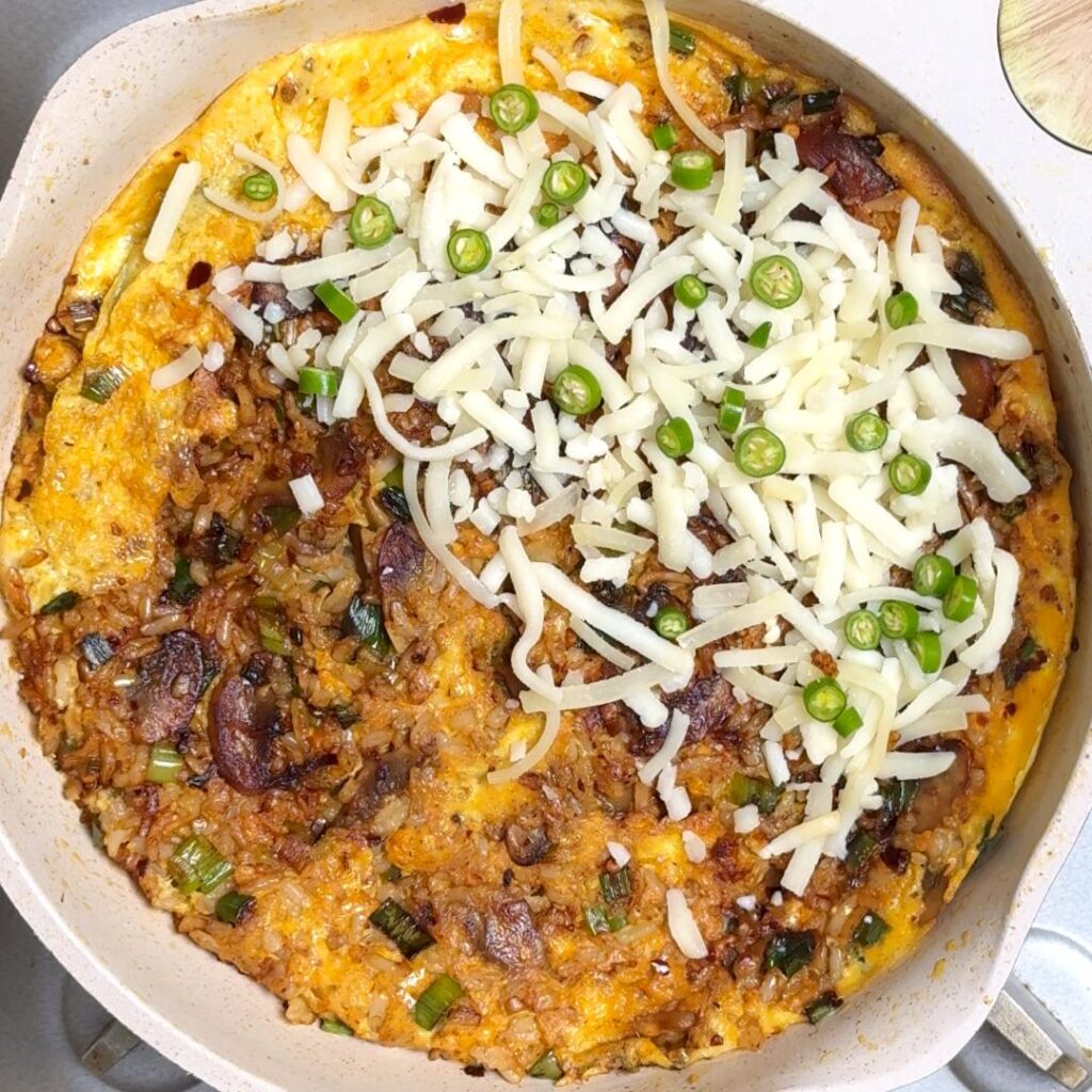 Once the bottom is cooked, flip the omelette, Add cheese on one half and top